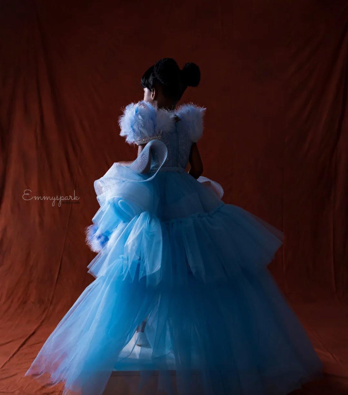 Child in elaborate blue tulle gown with feathered shoulders