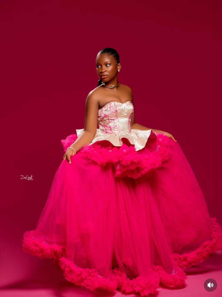 Woman in a vibrant pink ball gown with ornate bodice against a deep red background